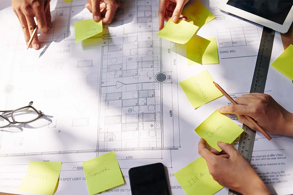 Mãos ao redor de um projeto com post-its amarelos
