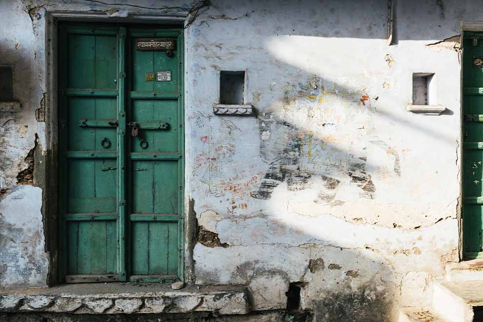 vista frontal de uma casa com grandes e perigosas rachaduras na entrada, com uma porta verde escura de madeira e pequenas janelas