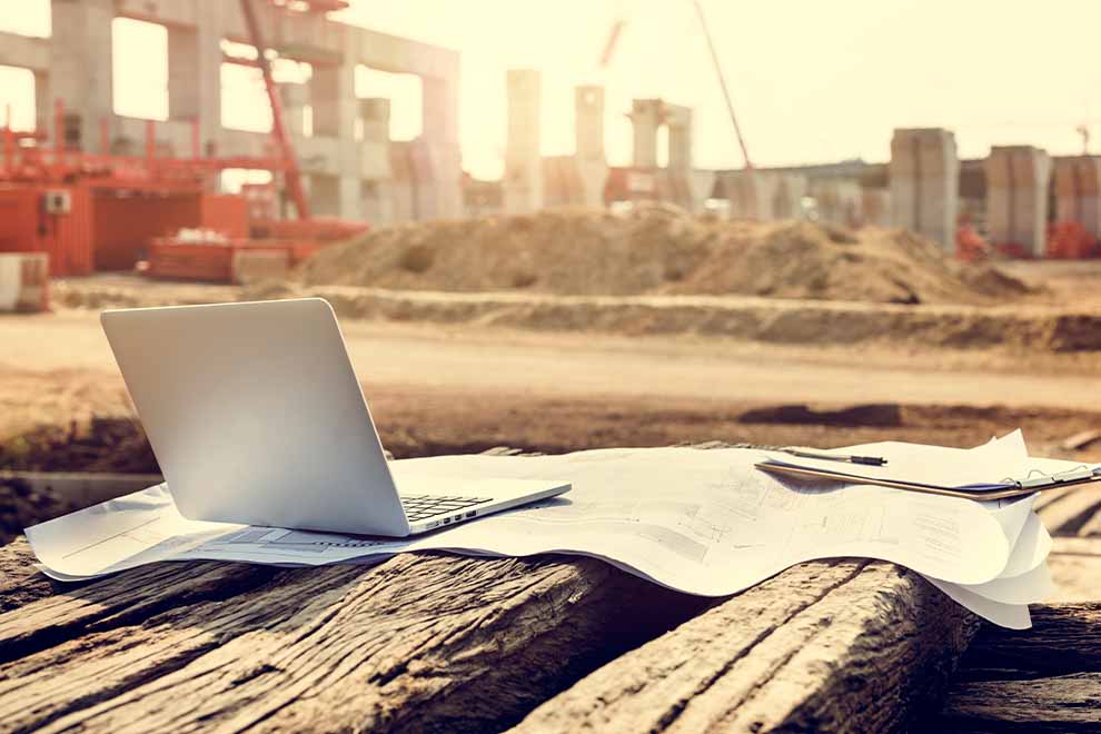 Laptop sobre planta de construção em obra