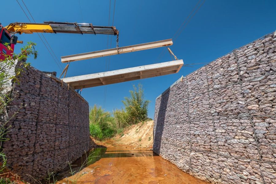 Ponte sendo colocada entre barragem feita por pedras